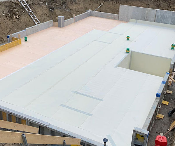 Auf der Baustelle wird die Bodenplatte aus WU-Beton mit Frischbetonverbundfolie ausgelegt. 